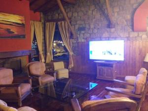 sala de estar con TV y pared de piedra. en Los Acantilados Hotel, en Puerto Deseado