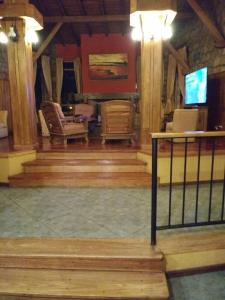 Una habitación con escaleras de madera y sillas y un televisor. en Los Acantilados Hotel, en Puerto Deseado