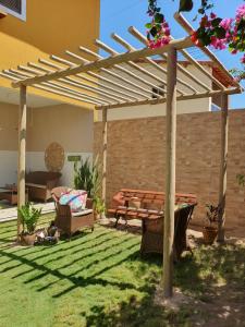 eine hölzerne Pergola mit einer Bank und einem Tisch in der Unterkunft Casa do Bougainvillea Mundaú-Trairi-Ce in Mundaú