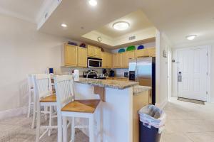 a kitchen with a counter with chairs and a refrigerator at Holiday Isle 618 in Dauphin Island