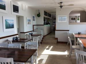 un restaurante con mesas de madera y sillas blancas en Discovery Bay en St Ouen's