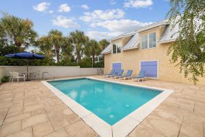 a swimming pool with chairs and an umbrella in front of a house at Always On My Mind by 30A Escapes in Seacrest