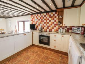 a kitchen with white cabinets and a tile floor at Cyffdy Cottage - Aran in Bala +12 photos