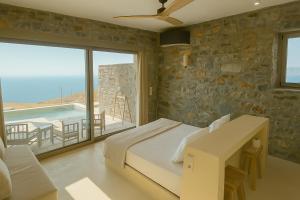 a bedroom with a bed and a balcony with a pool at Piperi Suites in Kithnos