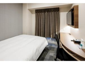 a hotel room with a bed and a desk and a television at Smile Hotel Okayama - Vacation STAY 60155v in Okayama