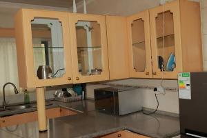 a kitchen with wooden cabinets and a microwave at Broadhurst Homestay in Gaborone