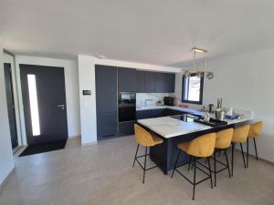 a kitchen with a kitchen island with yellow bar stools at Villa neuve avec piscine in Régusse