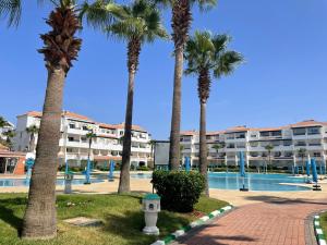 a group of palm trees next to a swimming pool at Garden Beach 2 in Sidi Rahal