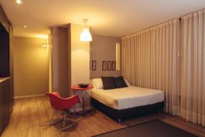 a hotel room with a bed and a red chair at Hotel Living 55 in Bogotá