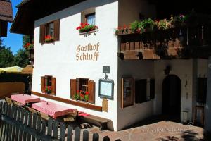 um edifício com mesas e flores ao lado em Gasthof Schluff em Soprabolzano