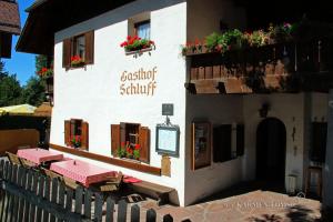 a building with tables and flowers on the side of it at Gasthof Schluff in Soprabolzano