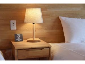 a lamp on a night stand next to a bed at Hotel Hanafuji Inn - Vacation STAY 82497v in Nakafurano