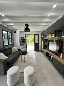 a living room with a couch and chairs and a tv at La Villa LIFE in La Plaine des Palmistes