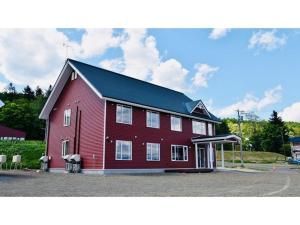 a large red barn with a black roof at Hotel Hanafuji Inn - Vacation STAY 82519v in Nakafurano