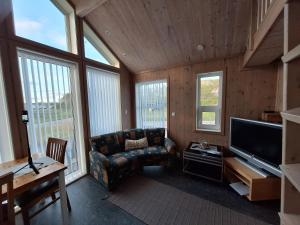 a living room with a couch and a tv at Atlanterhavsveien Rorbuer in Averoy