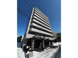 a tall building in the snow next to a street at Tokan Nakanoshima Castel - Vacation STAY 19498 in Sapporo