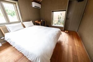 a bedroom with a large white bed and two windows at Shiraho Villa Square Court - Vacation STAY 63025v in Shiraho