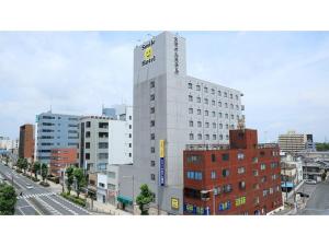 a tall white building with a sign on it in a city at Smile Hotel Kumagaya - Vacation STAY 64091v in Kumagaya