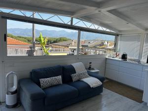 - un canapé bleu dans une chambre avec une grande fenêtre dans l'établissement Cosy Apartment with Terrace view in Sarzana Italy, à Marinella di Sarzana