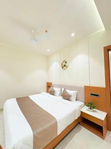 a bedroom with a large white bed with a table at Hotel vimlayatan in Ujjain