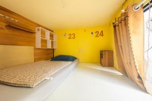 a bedroom with a bed and a yellow wall at Nestin by Little Garden in Ho Chi Minh City +32 photos