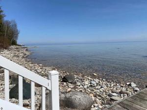 a white railing next to a body of water at Spectacular Suttons Bay Stay - Game Room Kayaks Pizza Oven & More in Suttons Bay