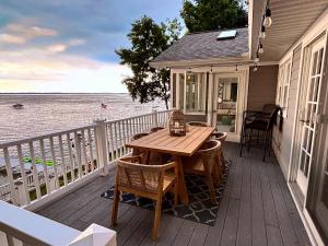 a wooden deck with a table and chairs on a house at Spectacular Suttons Bay Stay - Game Room Kayaks Pizza Oven & More in Suttons Bay