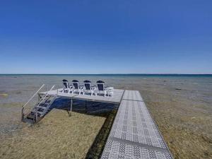 a deck with chairs on the beach at Spectacular Suttons Bay Stay - Game Room Kayaks Pizza Oven & More in Suttons Bay +85 photos