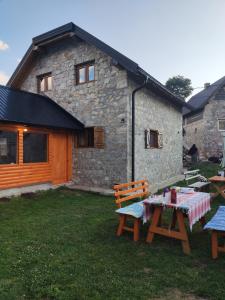 a picnic table in front of a stone building at Prenociste B&M - Lukomir in Lukomir