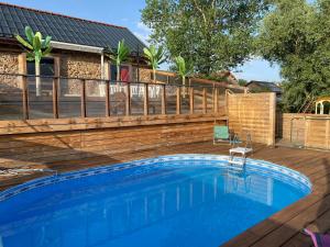 a swimming pool with a wooden deck and a fence at Roulottes des Combrailles in Saint-Pardoux