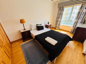 a bedroom with a bed with a black blanket and a window at Luxury apartment next Lisbon centre, super well connected in Queluz +11 photos