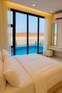 a bedroom with a large bed and large windows at Remal Resort in Bidiyah
