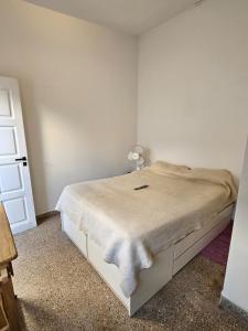 a white bedroom with a bed with a lamp on it at Sonido de mar in Santa Teresita