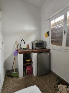 a small kitchen with a microwave on a table with a sink at Sonido de mar in Santa Teresita