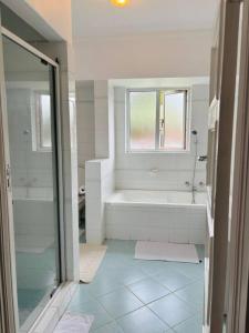 a white bathroom with a tub and a shower at The Cozy Corner Luxury Living in Nchesi