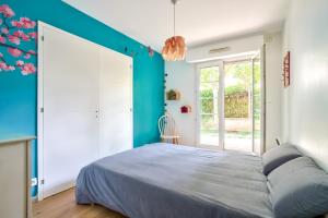 ein Schlafzimmer mit einem großen Bett und einer blauen Wand in der Unterkunft Grand et charmant appartement familial, 3 chambres, et moderne avec grand jardin et parking privatif aux portes de Paris in La Garenne-Colombes