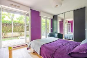 ein lila Schlafzimmer mit einem Bett und einem Fenster in der Unterkunft Grand et charmant appartement familial, 3 chambres, et moderne avec grand jardin et parking privatif aux portes de Paris in La Garenne-Colombes