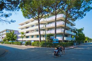 two people pushing a stroller down a street in front of a building at Residence Sabrina in Bibione