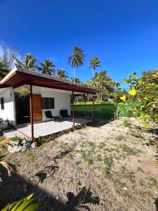 a small white house with a porch and palm trees at Ori Lodge Rangiroa in Rangiroa
