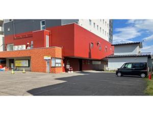 a red building with a car parked in a parking lot at Smile Hotel Tomakomai - Vacation STAY 68975v in Tomakomai