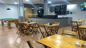 a restaurant with wooden tables and chairs and a bar at Hotel Avenida in Nova Friburgo