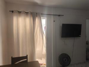 a living room with a television and a curtain at Apartamento Life COP30 in Castanhal