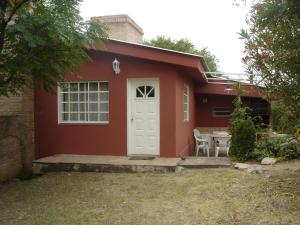 a red house with a white door and a table at Complejo Lago Chico in Tanti