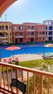 a balcony with a view of a pool with chairs and umbrellas at Porto matrouh chalets for family in Marsa Matruh