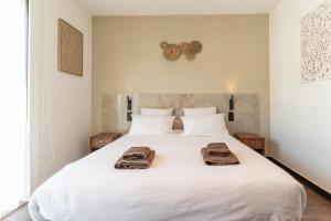 a bedroom with a white bed with towels on it at Les Sorbiers & spa in Saint-Avertin