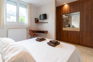 a bedroom with a white bed and a mirror at Les Sorbiers & spa in Saint-Avertin