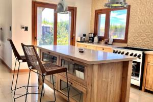 eine Küche mit einer großen Insel mit zwei Barhockern in der Unterkunft LUXURY Casa cerca al centro en El Calafate Glacial, Argentina in El Calafate + 11 Fotos