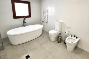ein weißes Badezimmer mit Badewanne und Toilette in der Unterkunft LUXURY Casa cerca al centro en El Calafate Glacial, Argentina in El Calafate