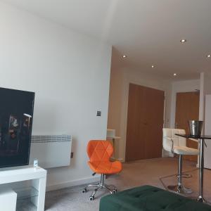 a living room with an orange chair and a television at Ensuite Double Bedroom, Live in landlord in Warrington +2 photos