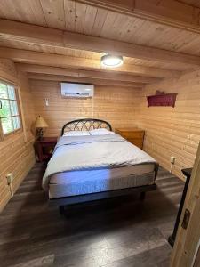 ein Schlafzimmer mit einem Bett in einer Blockhütte in der Unterkunft Lakeside Cottage On Muskoka Shores in Parry Sound